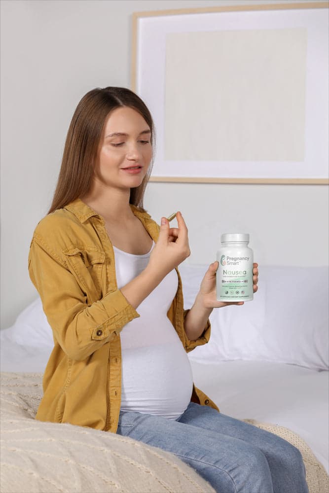 Expectant mother taking a Pregnancy Smart Nausea and Digestive Support capsule at home